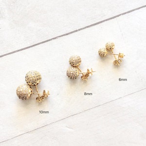 Three pairs of gold tone earrings with clear cubic zirconia stones. The earrings are shown in three sizes: 6mm, 8mm, and 10mm.