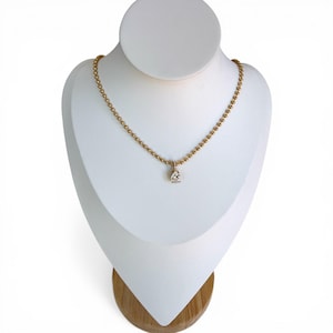 Pear cubic zirconia teardrop pendant necklace on white jewelry bust showing 18K PVD gold 3mm ball chain with pavé bail and sparkling CZ stone