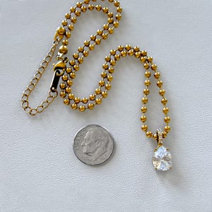 18K PVD gold ball chain with pear CZ pendant next to dime for scale showing actual pendant and chain size reference