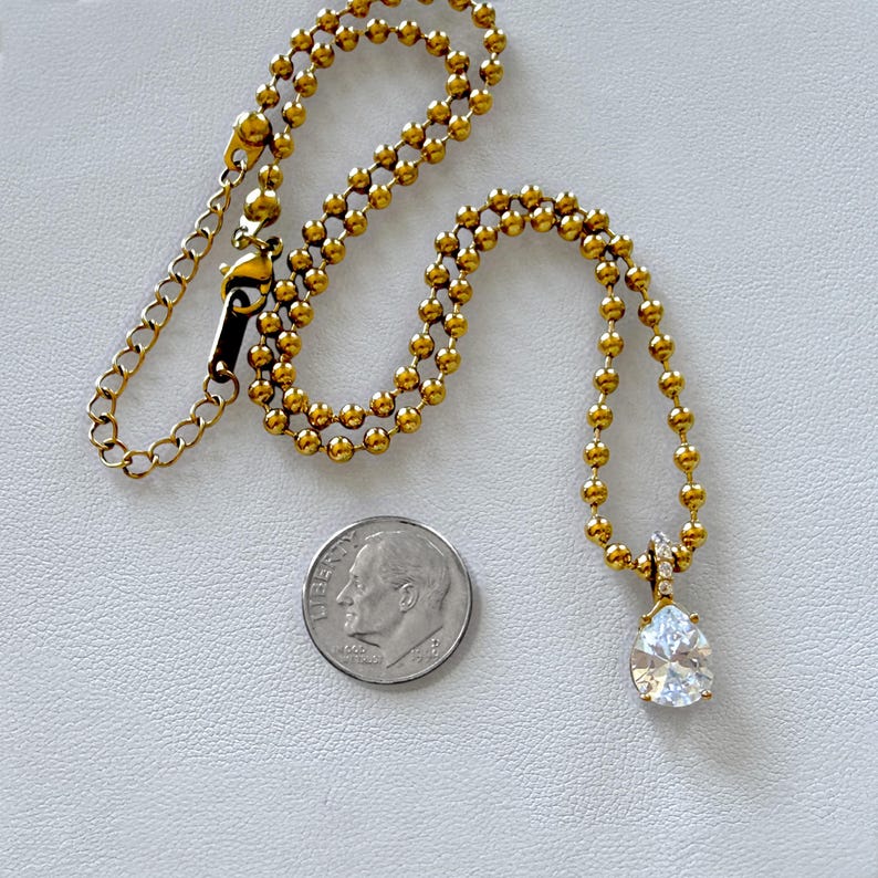 18K PVD gold ball chain with pear CZ pendant next to dime for scale showing actual pendant and chain size reference