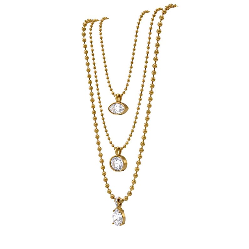Three gold CZ pendant necklaces laid flat showing oval marquise and pear cubic zirconia styles layered together on 18K PVD gold ball chains