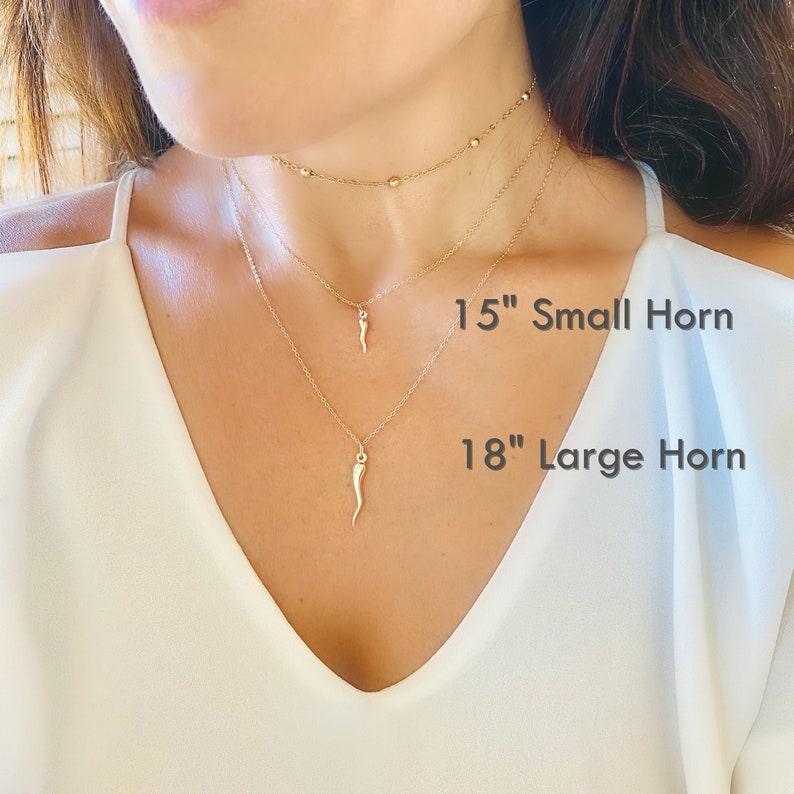 Necklace with horn shaped pendants, that can be worn in short or long lengths. Horn pendant comes in different sizes, a small horn and a large horn. Model is wearing both sizes to display the difference in size.