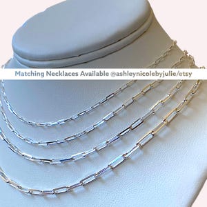 May include: Four silver chain necklaces of varying lengths, layered on a white mannequin bust. The necklaces are made of small, rectangular links. The text "Matching Necklaces Available @ashleynicolebyjulie/etsy" is displayed above the necklaces.