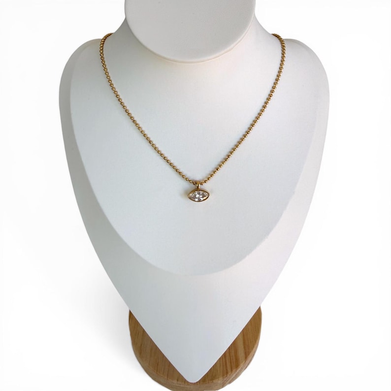 Marquise cubic zirconia pendant necklace on white jewelry bust showing 18K PVD gold 2mm ball chain with bezel set CZ pendant, style 1