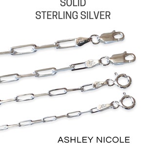 May include: Four different lengths of solid sterling silver chain necklaces with a lobster clasp closure. The chains are made of small, rectangular links. The image is zoomed in to show the details of the chains.