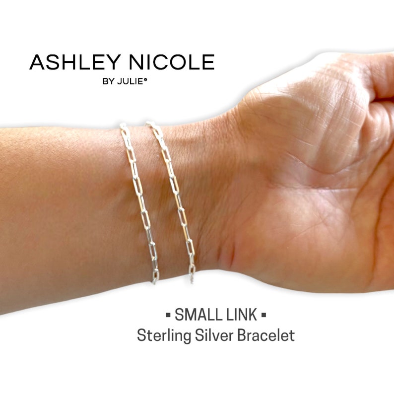 May include: A silver chain bracelet with small links. The bracelet is on a person's wrist. The text "SMALL LINK" and "Sterling Silver Bracelet" is below the bracelet.