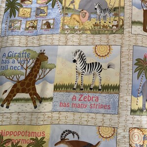 May include: A colorful fabric with a jungle theme. The fabric features illustrations of animals like a giraffe, zebra, hippopotamus, and a monkey. The text on the fabric says "Sunny Jungle Fun" and "A Giraffe has a very tall neck".