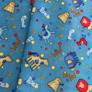 May include: A light blue fabric featuring cartoon animals like giraffes, dogs, lions, and elephants. The fabric is decorated with colorful polka dots and animal sound effects such as "Woof", "Roar", and "Neigh".