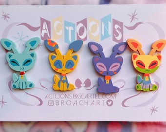 Puede incluir: Cuatro pines de animales de dibujos animados coloridos con un diseño retro. Los pines presentan una criatura extraterrestre azul, amarilla, morada y naranja con ojos grandes y una expresión amigable. Los pines se muestran en una tarjeta blanca con el texto "ACTOONS" en una fuente retro.
