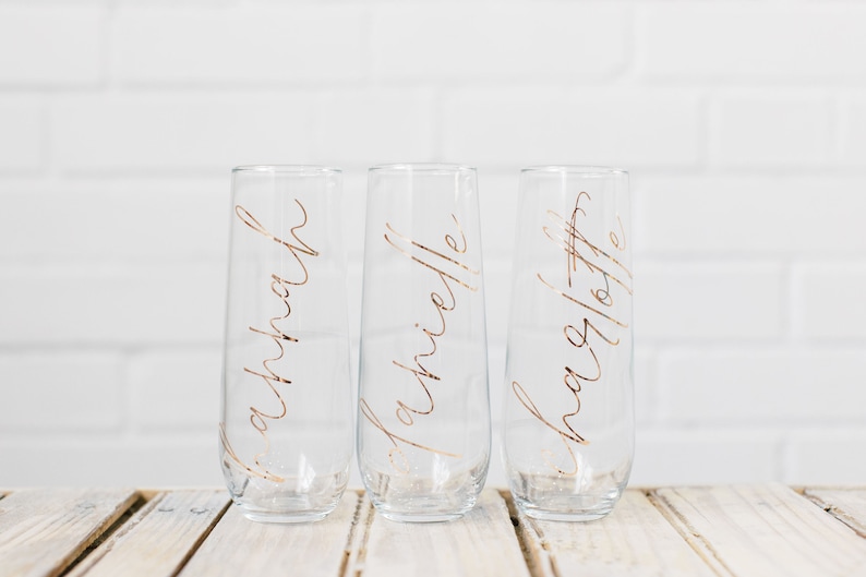 May include: Three clear glass champagne flutes with gold lettering. The flutes are labeled "Savannah", "Michelle", and "Shana Lofte".