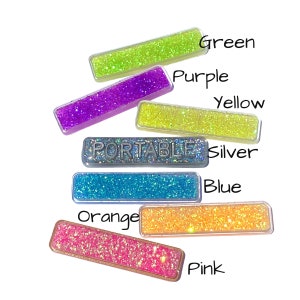 May include: A collection of rectangular, glitter-filled accessories in various colors: green, purple, yellow, silver, blue, orange, and pink. The word "PORTABLE" is displayed on one of the rectangles. Each rectangle has a clear border.