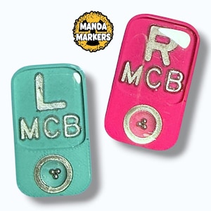 May include: Two rectangular markers, one teal and one pink, with silver lettering and a circular silver accent. The teal marker has an "L" and the pink marker has an "R". Both markers have "MCB" text. The top left corner has a logo that says "Manda Markers".