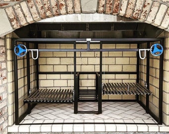 Op de afbeelding: Een zwarte metalen buiten grill met twee verstelbare grillroosters. De grill is ingebouwd in een bakstenen muur en heeft aan elke kant twee blauwe wielen.