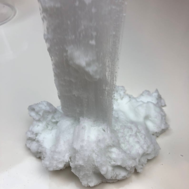 May include: White fluffy slime being poured from a container. The slime is thick and gooey, and it looks like it would be fun to play with.