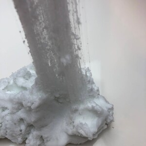 May include: White slime being pulled from a large pile of white slime. The slime has a grainy texture.