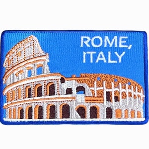 May include: A blue embroidered patch with a white outline featuring the Colosseum in Rome, Italy. The text "ROME, ITALY" is embroidered in white on a blue background.