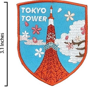 Pode incluir: Patch bordado com a Torre de Tóquio e flores de cerejeira. O patch em forma de escudo tem um fundo azul e uma borda laranja. A Torre de Tóquio é vermelha e branca. O patch mede 6,35 cm de largura e 7,87 cm de altura.