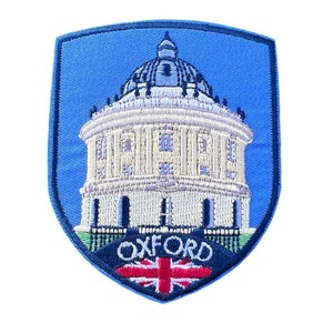 May include: A blue and white embroidered patch featuring a building and the word "OXFORD" in black text. A small red, white and blue flag is below the text.