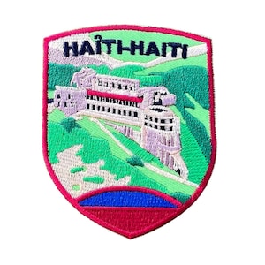 May include: Embroidered patch with a shield shape, featuring a building on a hillside. The patch has a red border, green background, and blue and red accents. The text "HAITI-HAITI" is at the top of the patch.