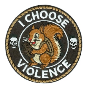 May include: Circular patch with a brown border and centre. It features a cartoon squirrel holding a nut, with the text "I CHOOSE VIOLENCE" in white. Two white skulls are on either side of the squirrel.