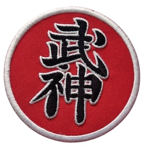 Peut inclure: Écusson brodé avec un fond rouge et une bordure blanche. L'écusson présente des caractères japonais noirs. Le design est circulaire.