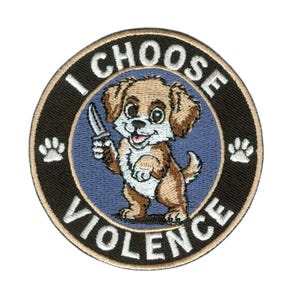 May include: Circular embroidered patch with a black border and the text "I CHOOSE VIOLENCE". The patch features a cartoon puppy holding a knife, set against a blue background. The puppy is brown and white, with paw prints on either side.