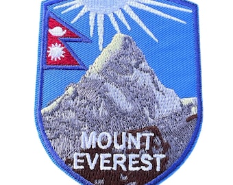 Puede incluir: Un parche bordado azul y blanco con una montaña y el texto "MOUNT EVEREST". El parche presenta un sol blanco con rayos y una bandera roja y azul de Nepal.