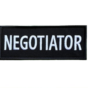 Peut inclure: Écusson brodé noir avec du texte blanc qui dit "NÉGOCIATEUR".