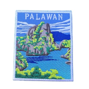 May include: An embroidered patch with a blue background and white border. The patch features a scenic view of a rocky island with green trees and a blue body of water. The text "PALAWAN" is embroidered in white at the top of the patch.