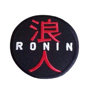 Può includere: Una toppa ricamata nera e rossa con la parola "RONIN" in lettere bianche e un carattere giapponese in rosso.