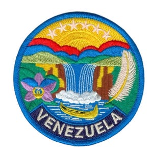 Könnte beinhalten: Runder, gestickter Aufnäher mit dem venezolanischen Wappen. Das Design umfasst einen Wasserfall, eine gelbe Sonne, eine Feder und eine Blume, vor blauem Hintergrund. Das Wort "VENEZUELA" ist abgebildet.