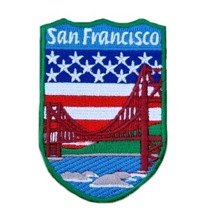 Op de afbeelding: Geborduurde patch met een rood, wit en blauwe Amerikaanse vlag en de Golden Gate Bridge in San Francisco, Californië. De patch is groen en heeft de tekst "San Francisco" erop.