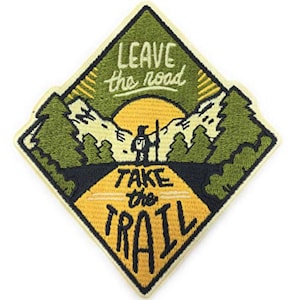 May include: A yellow diamond-shaped embroidered patch with a hiker on a trail in a green forest. The text on the patch reads "Leave the road Take the TRAIL".