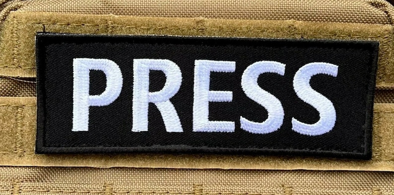 Peut inclure: Un patch noir avec du texte brod&eacute; en blanc qui dit "PRESS".