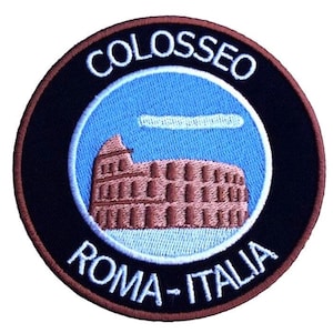 May include: A round, black and brown embroidered patch with a white outline. The patch features a blue sky with a white cloud and a brown image of the Colosseum in Rome, Italy. The text "COLOSSEO ROMA - ITALIA" is embroidered in white on the patch.