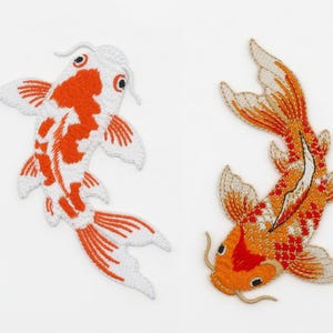 May include: Two embroidered koi fish patches. One is white and orange, the other is orange and white. The patches are detailed with fins, tails, and facial features. The koi fish are a symbol of good fortune.