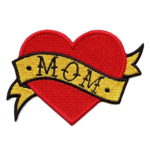 Könnte beinhalten: Rotes Herz mit einem gelben Banner, auf dem "MOM" in schwarzen Buchstaben steht. Herz und Banner sind gestickt.