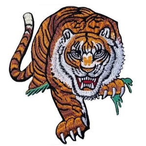 Könnte beinhalten: Gestickter Bügel-Aufnäher mit einem knurrenden orangefarbenen und weißen Tiger mit grünem Laub. Der Tiger blickt nach vorne, mit offenem Maul und ausgestreckten Krallen.