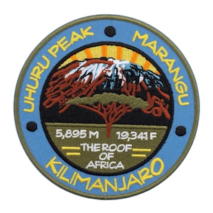 May include: Embroidered patch featuring a mountain landscape with the text "Uhuru Peak Marangu Kilimanjaro". The patch includes the text "The Roof of Africa" and the elevation in meters and feet. The patch has a blue border.