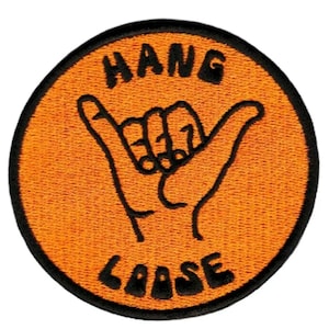 Op de afbeelding: Oranje en zwarte geborduurde patch met een hand die de "hang loose"-beweging maakt en de tekst "HANG LOOSE".