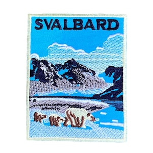 Może przedstawiać: Naszywka haftowana z niebieskim tłem i białym obramowaniem. Naszywka przedstawia pasmo górskie, zbiornik wodny i trzy niedźwiedzie polarne. Tekst "SVALBARD" znajduje się na górze naszywki.