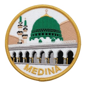 May include: Embroidered patch featuring a green-domed mosque with minarets, set against a tan background. The patch is circular, with a gold border and the word "MEDINA" in gold lettering at the bottom. The design is detailed and colorful.