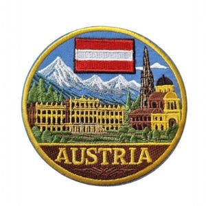 Może przedstawiać: Haftowana naszywka z austriacką flagą i zabytkami. Projekt zawiera austriacką flagę, ośnieżone góry i detale architektoniczne. Słowo "AUSTRIA" jest wyhaftowane złotą nicią.