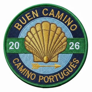 Può includere: Toppa ricamata con la scritta "BUEN CAMINO CAMINO PORTUGUÊS 2026". La toppa presenta una conchiglia dorata, una freccia e una combinazione di colori verde e blu.