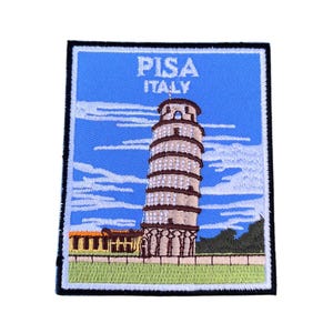 Op de afbeelding: Geborduurde patch met de scheve toren van Pisa in Pisa, Italië. De patch is blauw met witte wolken en groen gras. De tekst "PISA ITALY" is geborduurd in wit.