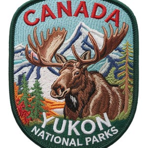 Könnte beinhalten: Gestickter Aufnäher mit einem Elch mit großem Geweih, vor dem Hintergrund von Bergen und Bäumen. Der Aufnäher trägt die Aufschrift "CANADA" in Rot und "YUKON NATIONAL PARKS" in Weiß, alles in einem grünen Rand.