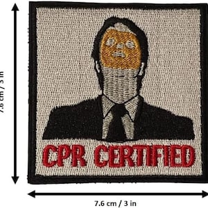 May include: A grey and black embroidered patch with a cartoon image of a man with a yellow face and the text "CPR CERTIFIED" in red.