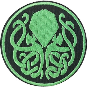 Könnte beinhalten: Grüner gestickter Aufnäher mit einem kreisförmigen Design einer tentakelartigen Kreatur auf schwarzem Hintergrund.