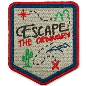 May include: A beige embroidered patch with a red border. The patch features a map with a dotted line, a cactus, mountains, and a red X. The text "ESCAPE' THE ORDINARY" is written in black.