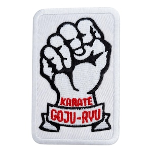 Pode incluir: Patch retangular branco com um design Karate Goju-Ryu preto e vermelho. O patch apresenta um punho cerrado em preto com as palavras "KARATE" e "GOJU-RYU" em vermelho em uma faixa.